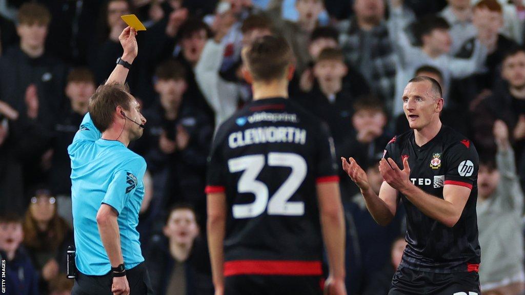 Referee Sam Purkiss shows a second yellow card to Wrexham's Will Boyle during their draw at MK Dons