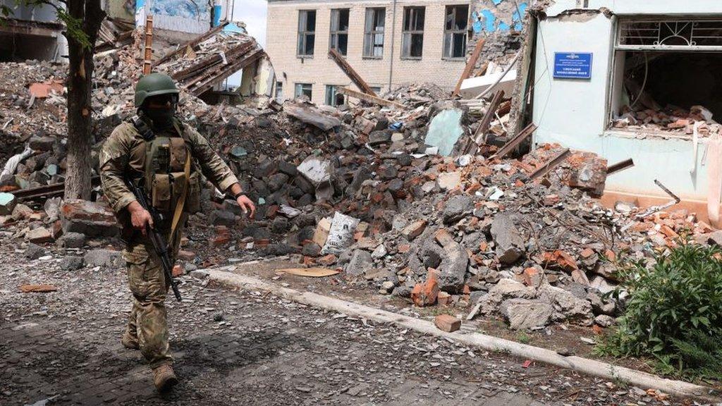 A Ukrainian serviceman passes by destroyed buildings in the Ukrainian town of Siversk, Donetsk region on July 22, 2022