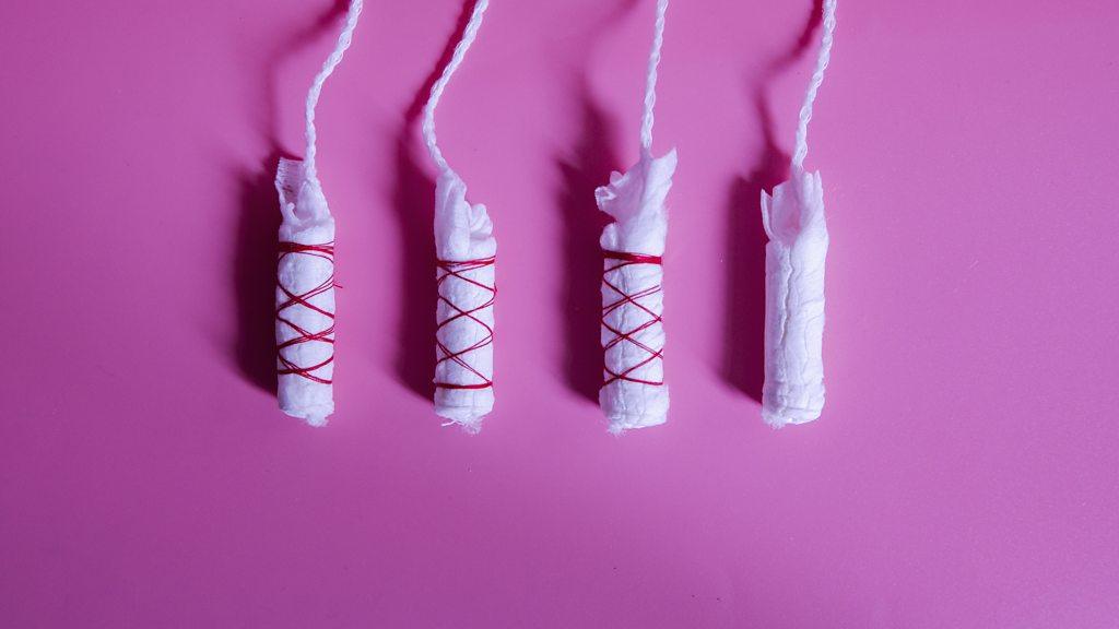 Four tampons, three have red cotton tied around them.