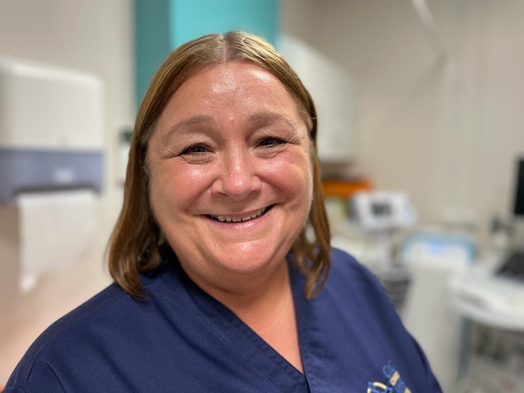 Claire is wearing a dark blue nurses' uniform and is in one of the treatment rooms of the gynae hub.