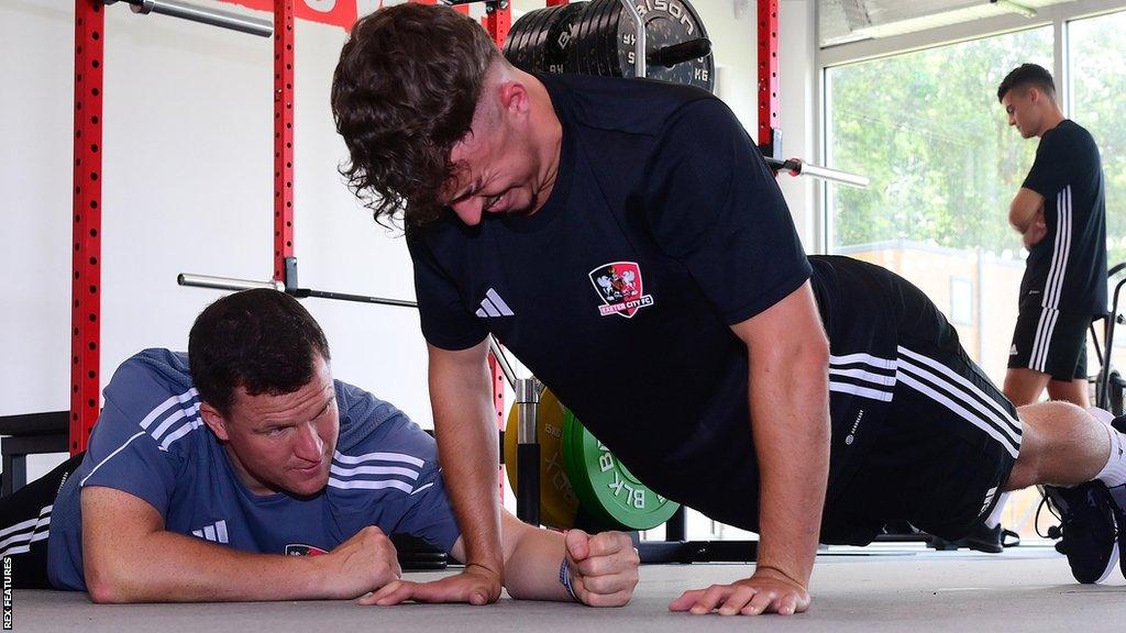 Gary Caldwell encourages an Exeter player doing press-ups in pre-season