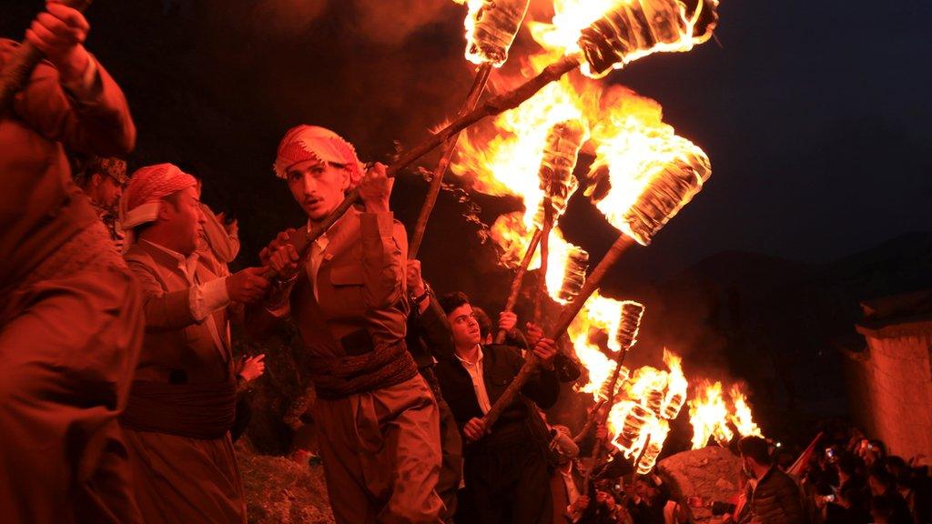 Iraqi Kurdish people carry fire torches, as they celebrate Nowruz Day, a festival marking the first day of spring and the new year, amid the spread of the coronavirus disease (COVID-19), in the town of Akra near Duhok, in Iraqi Kurdistan