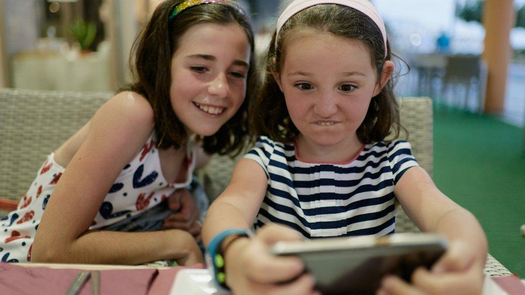 Stock image of two girls using a phone