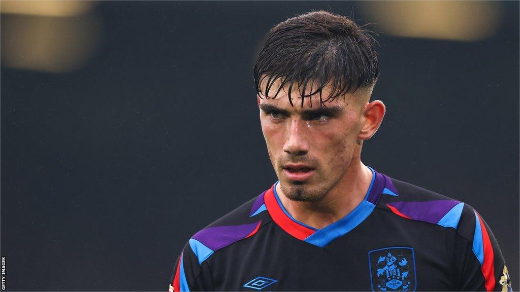 Kian Harratt stands in the rain for Huddersfield at Leeds