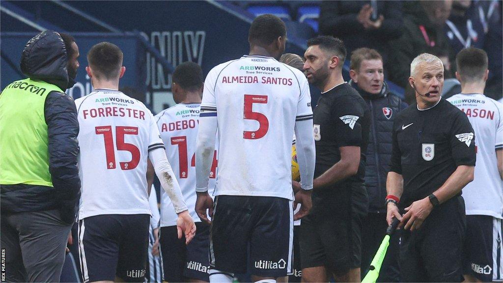 Referee Sunny Singh Gill leads the players off the pitch