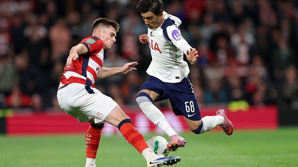 Luca Williams-Barnett of Tottenham Hotspur is tackled by Sean Grehan of Doncaster Rovers on a football pitch