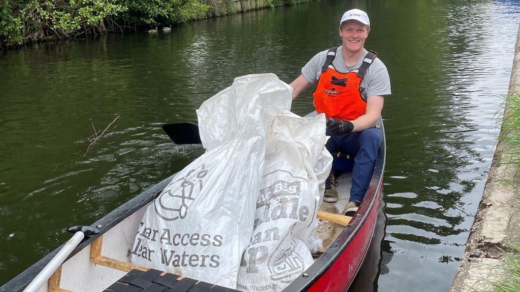 Tom Lusty with full rubbish bags after a Paddle Cleanup drive