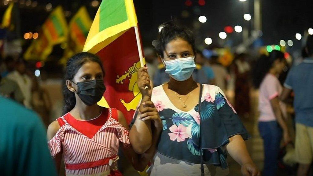 Two women hold a flag at Galle Face protest