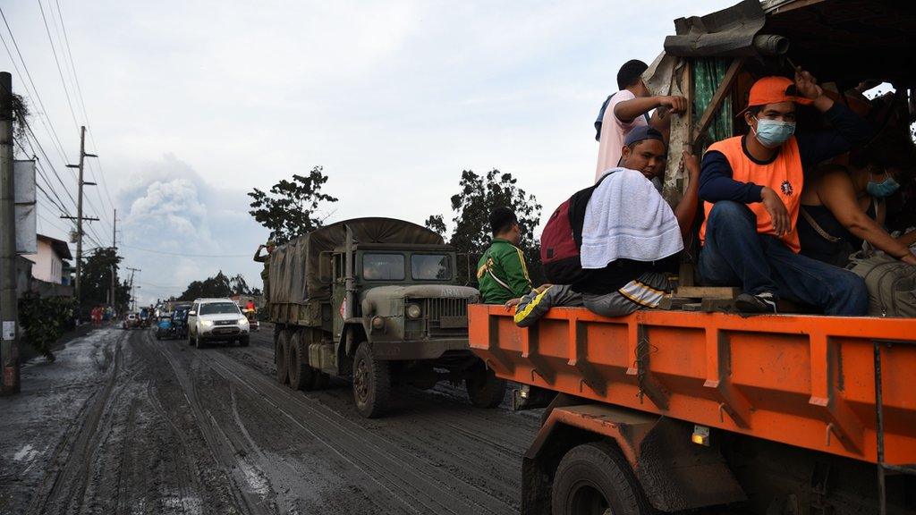 Residents aboard a government truck evacuate to a safer place after Taal volcano began spewing ash over Tanauan town, Batangas province south of Manila on January 13