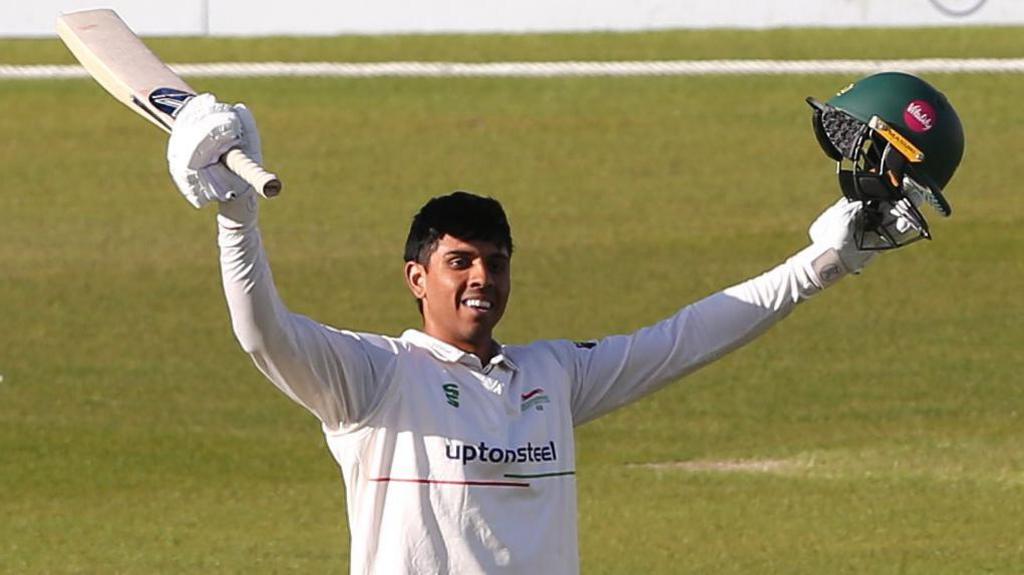 Rishi Patel raises his arms after scoring a century for Leicestershire