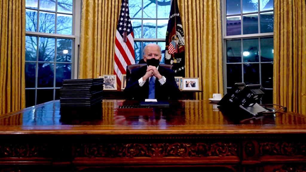 Joe Biden sits in the Oval Office