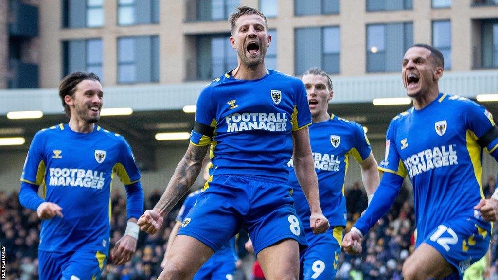 Harry Pell (centre) celebrates a goal for AFC Wimbledon