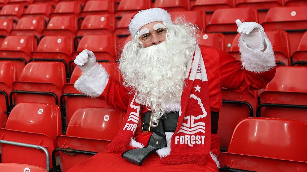 A Santa Claus wearing a Nottingham Forest scarf looks on from the stands 