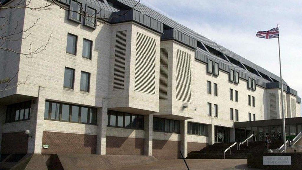 A large concrete court building with a union jack flag waving outside