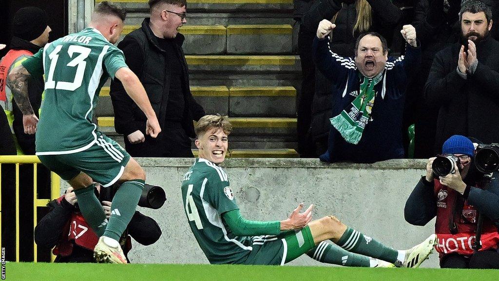 Isaac Price slides on the Windsor Park turf after putting Northern Ireland ahead against Denmark