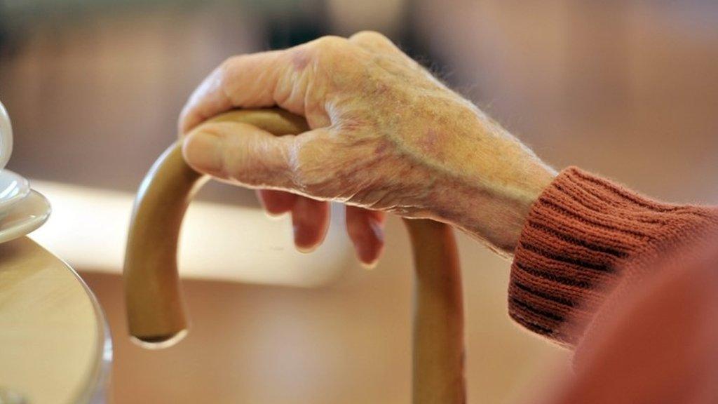 Older person's hand on walking stick