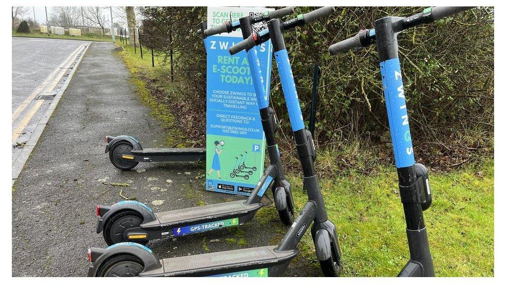 Four blue scooters lined up on a pavement