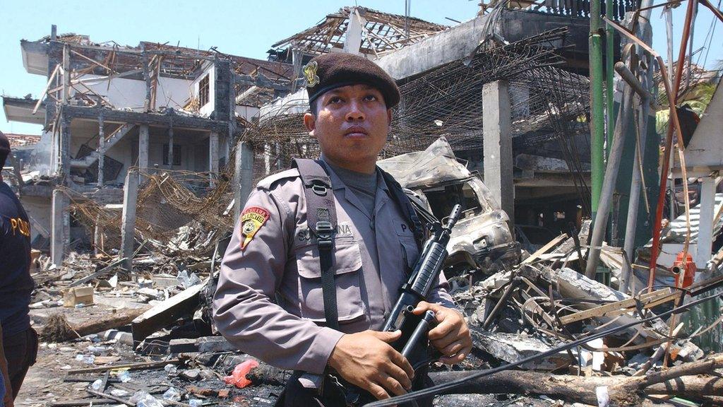 An armed Indonesian policeman guards what remains of a nightclub in the aftermath of the Bali bombing in October 2002.