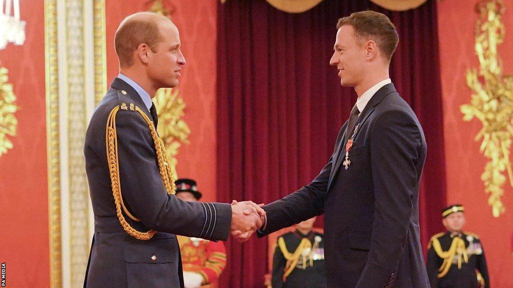 The Prince of Wales presents Jonny Evans with his MBE at Buckingham Palace