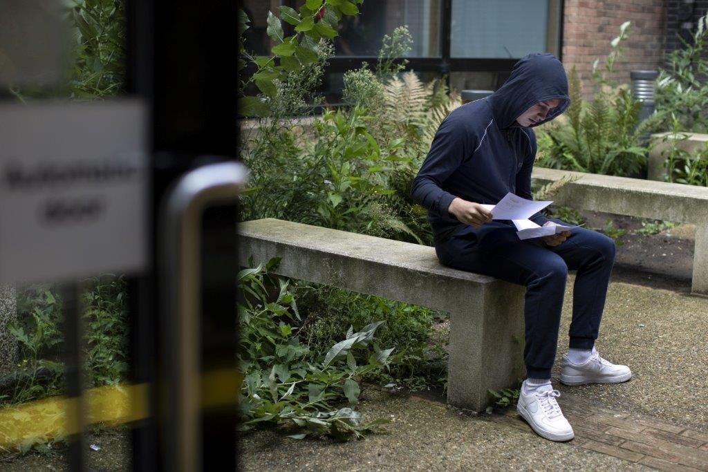 Boy on bench with results papers