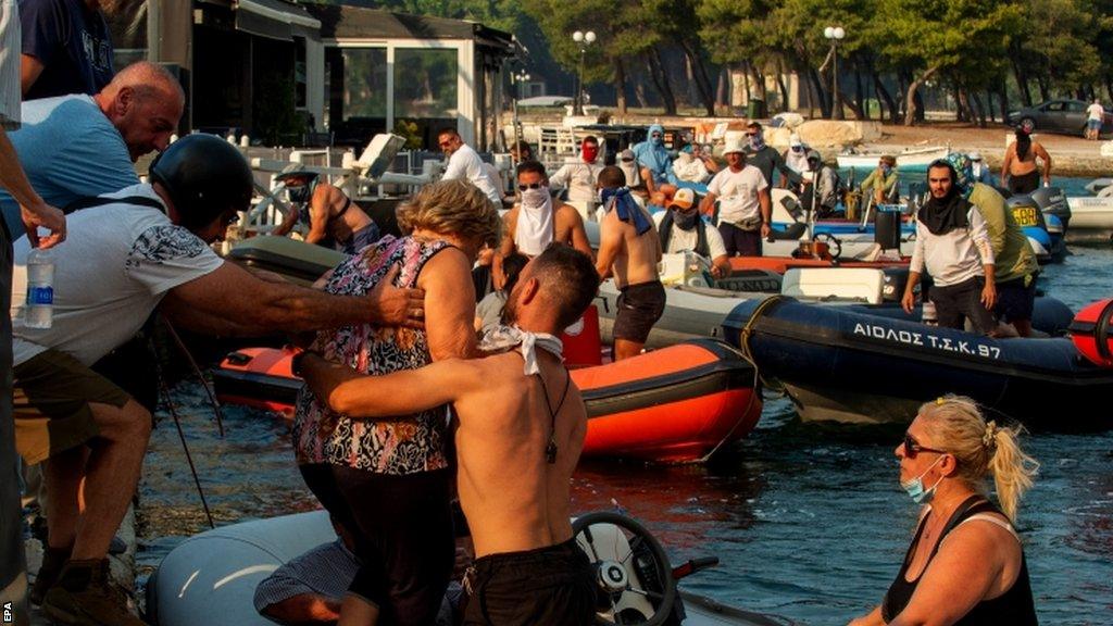 Peopled being evacuate by boats during a wildfire at Nea Anchialos