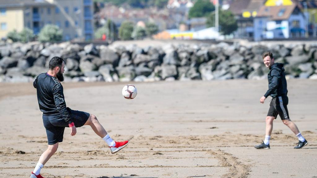 People play football on beach