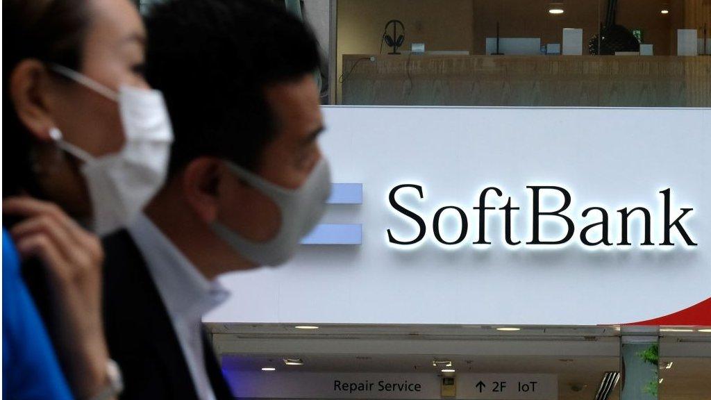 Pedestrians walk past a Japan's SoftBank mobile shop in Tokyo.