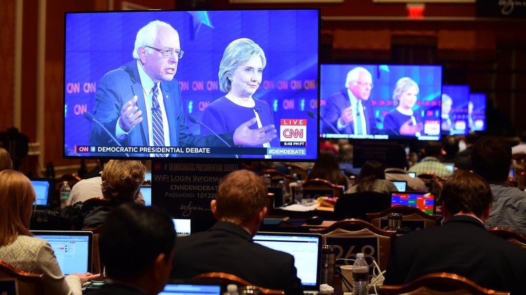 Screens show Sanders and Clinton