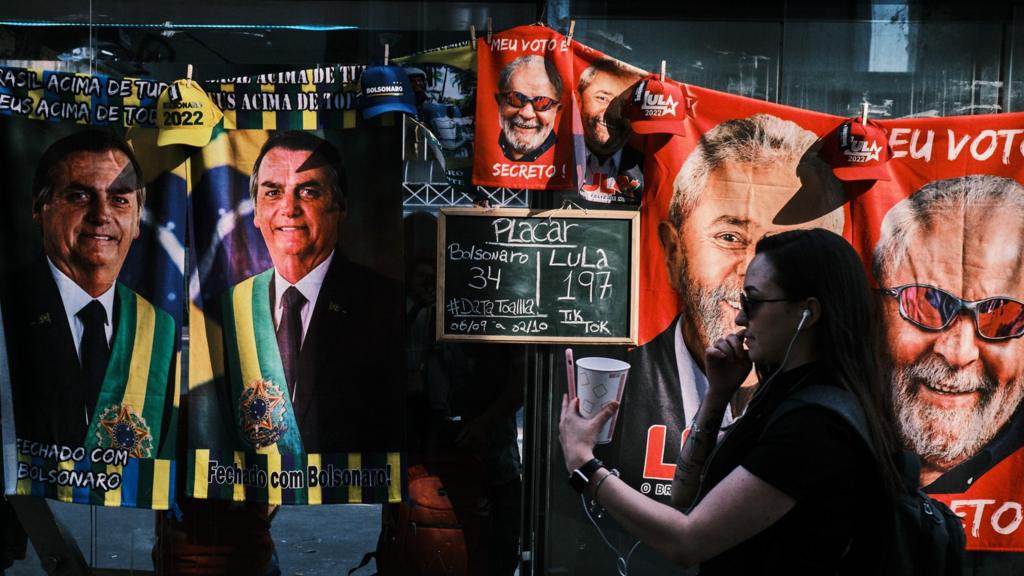 A woman walks by a street stall selling towels of presidential candidates Luis Inacio Lula da Silva and Jair Bolsonaro at Paulista avenue on September 23, 2022 in Sao Paulo, Brazil