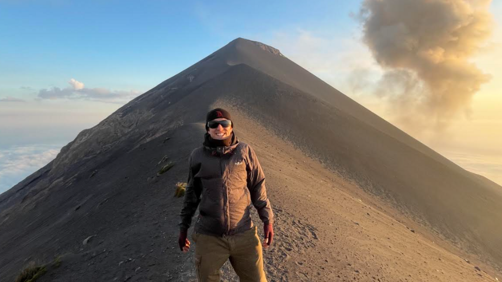 Alex Gordon smiles for the camera on top of an ash-covered volcano.