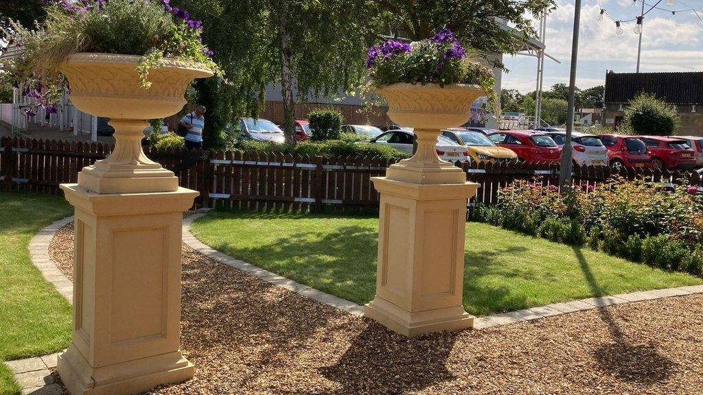 Gravel path leading to two stone plinths