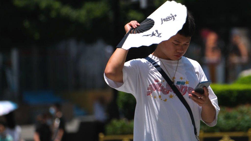 A man shields himself with a fan against heat wave on July 14, 2022 in Chongqing, China