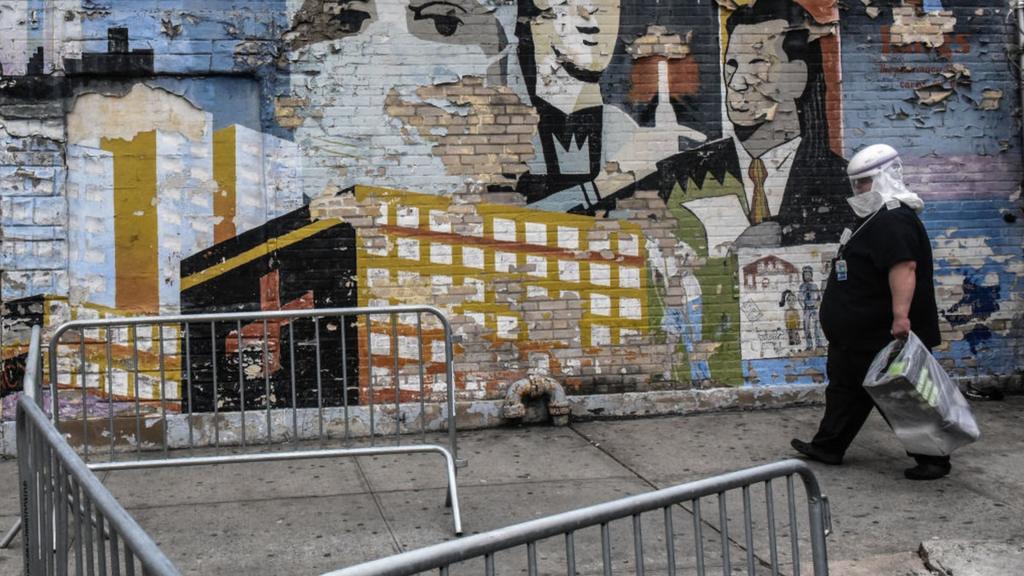 A health worker in PPE passes street art in Brooklyn