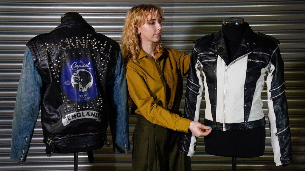 A Propstore employee adjusts Michael Jackson's custom-made leather jacket from a 1984 Pepsi New Generation commercial, which is next to George Michael's screen matched La Rocka Jacket from the music video for 'I Knew You Were Waiting (For Me)' during a preview for the Entertainment Memorabilia Auction, at the Propstore in Rickmansworth, Hertfordshire.