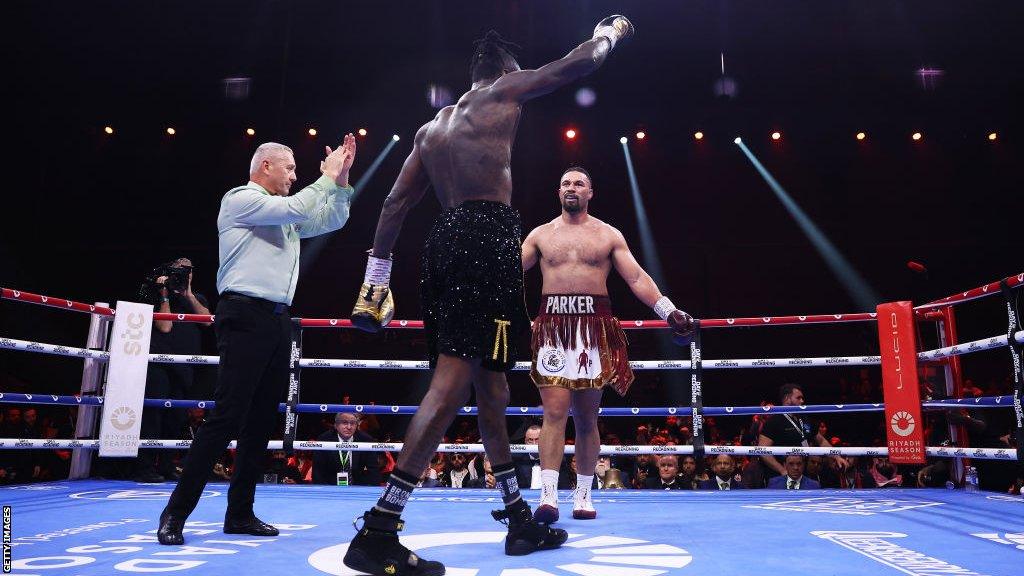 Deontay Wilder raises his hand in victory as Joseph Parker looks on bemused