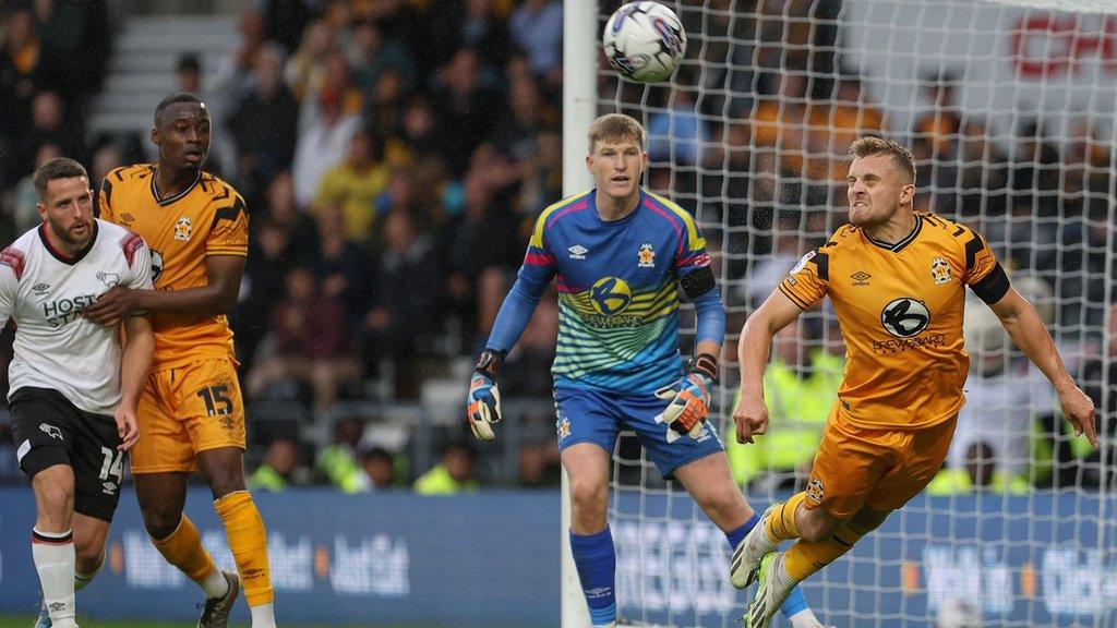 George Thomas heads the ball away from the Cambridge box against Derby