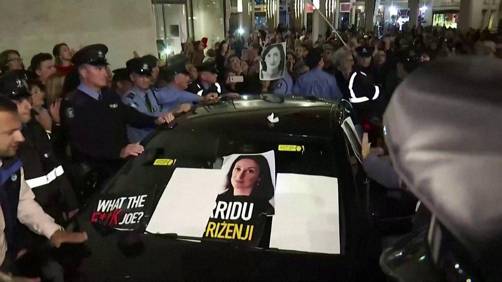 Protesters surround a car