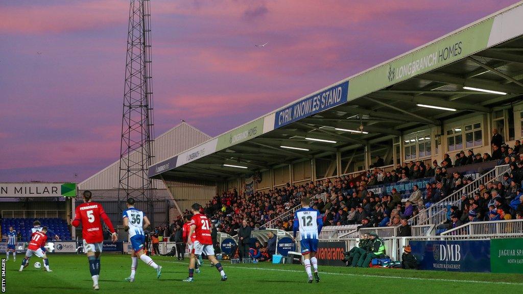 Hartlepool United players on the pitch mid-game in front of the Cyril Knowles Stand