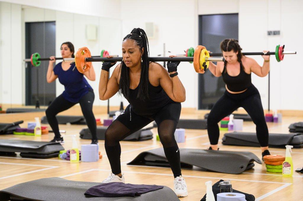 A group takes part in a high energy barbell class just after midnight at an indoor group exercise studio at Park Road Pools & Fitness