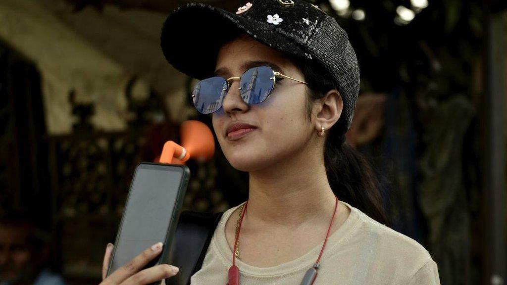 woman cools herself with phone fan