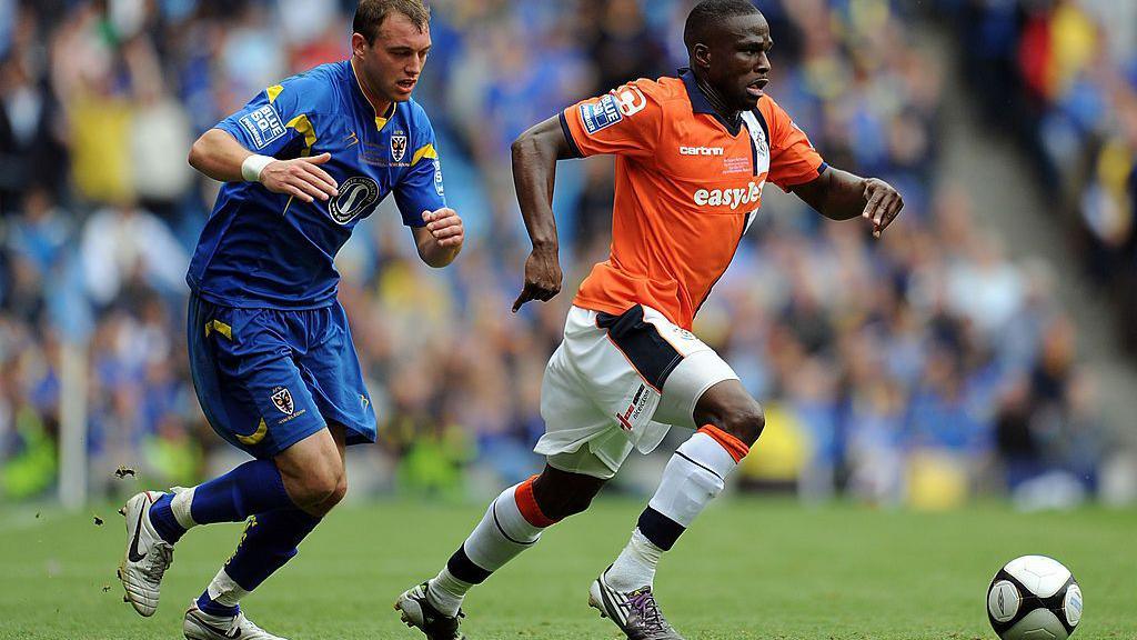 Brett Johnson of AFC Wimbledon chases Claude Gnakpa of Luton Town