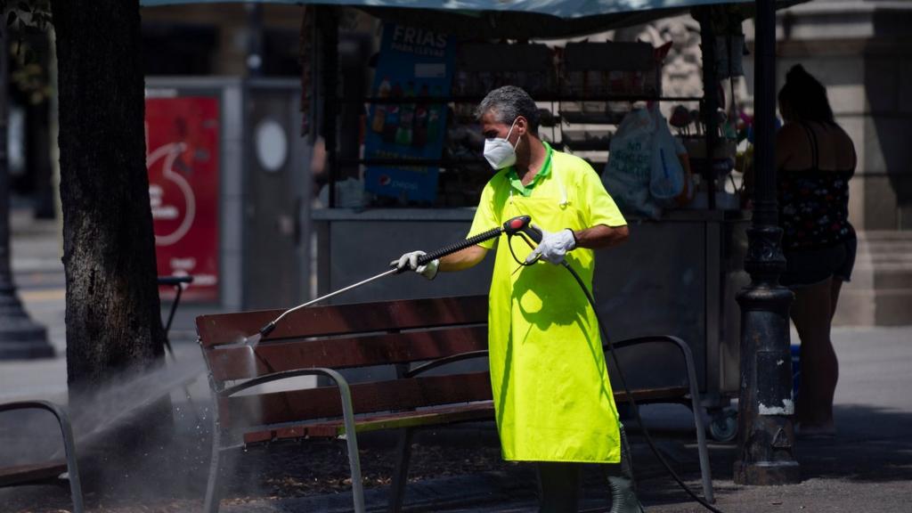 A municipal worker cleans a bench at Catalonia square in Barcelona on July 18, 2020.