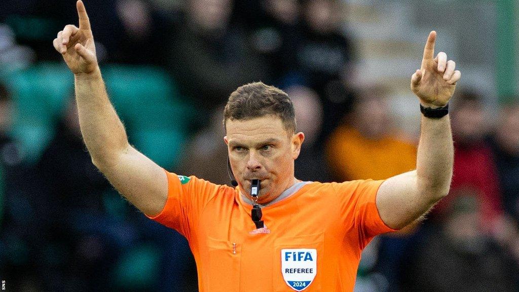 John Beaton with the whistle in his mouth and arms raised on refereeing duty