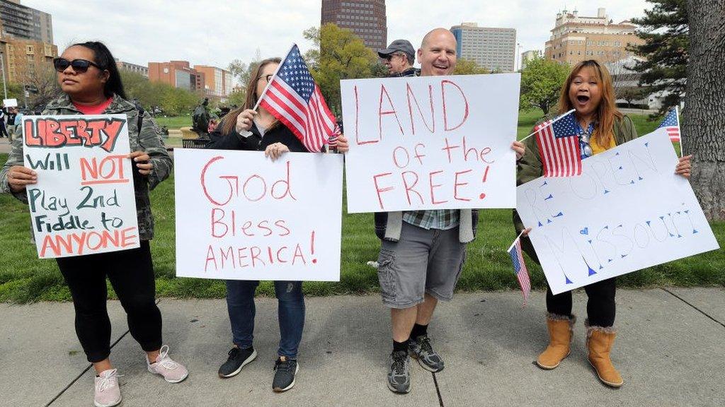 Protesters hold signs encouraging people to demand that businesses be allowed to open up in Kansas City, Missouri.