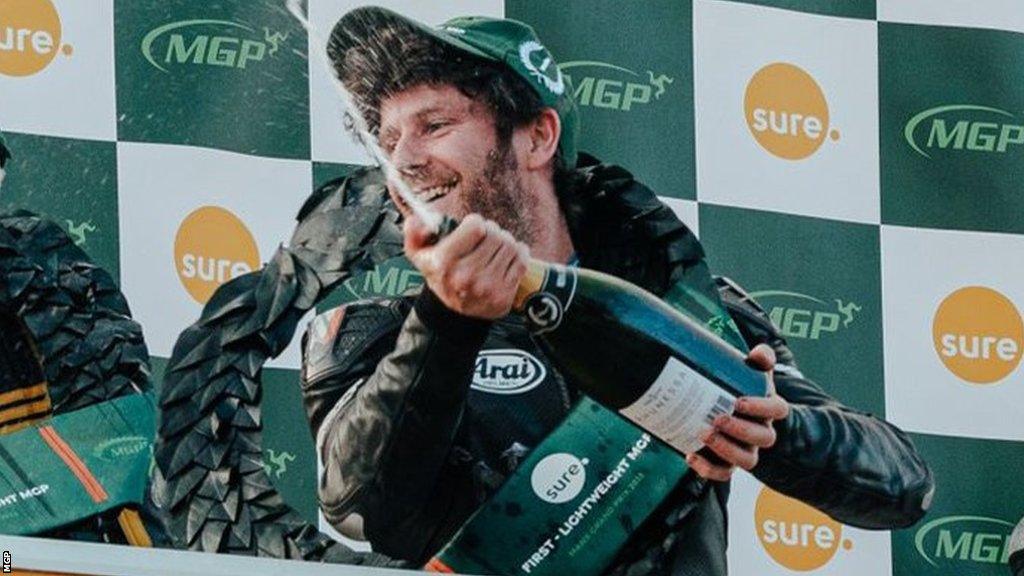 Mike Browne pops a bottle of champagne on the podium after winning the Lightweight Manx GP