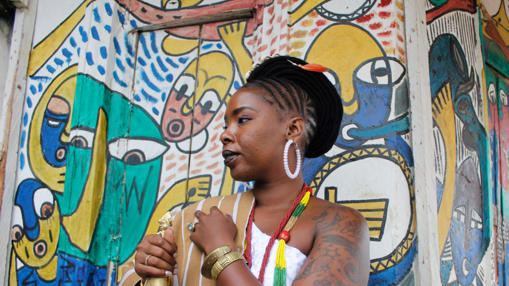 A woman in Osogbo, in Nigeria, standing in front of a decorated building