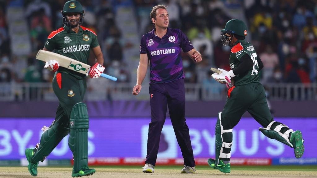 Josh Davey of Scotland looks on as Shakib Al Hasan and Mushfiqur Rahim of Bangladesh run between the wickets during the ICC Men's T20 World Cup match between Bangladesh and Scotland