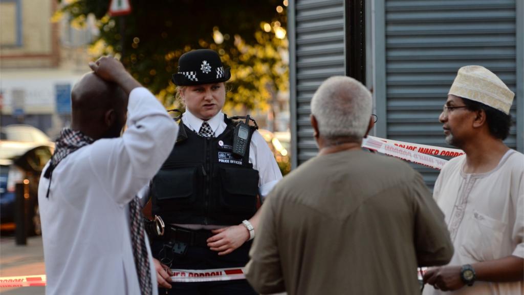 A police officer talks to local people at Finsbury Park in north London, where one man has died, eight people taken to hospital