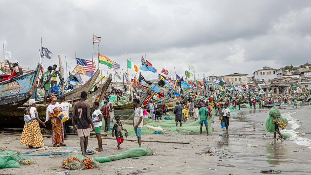 Fishermen tend to their boats on the shores of Cape Coast Castle in Ghana - October 2023