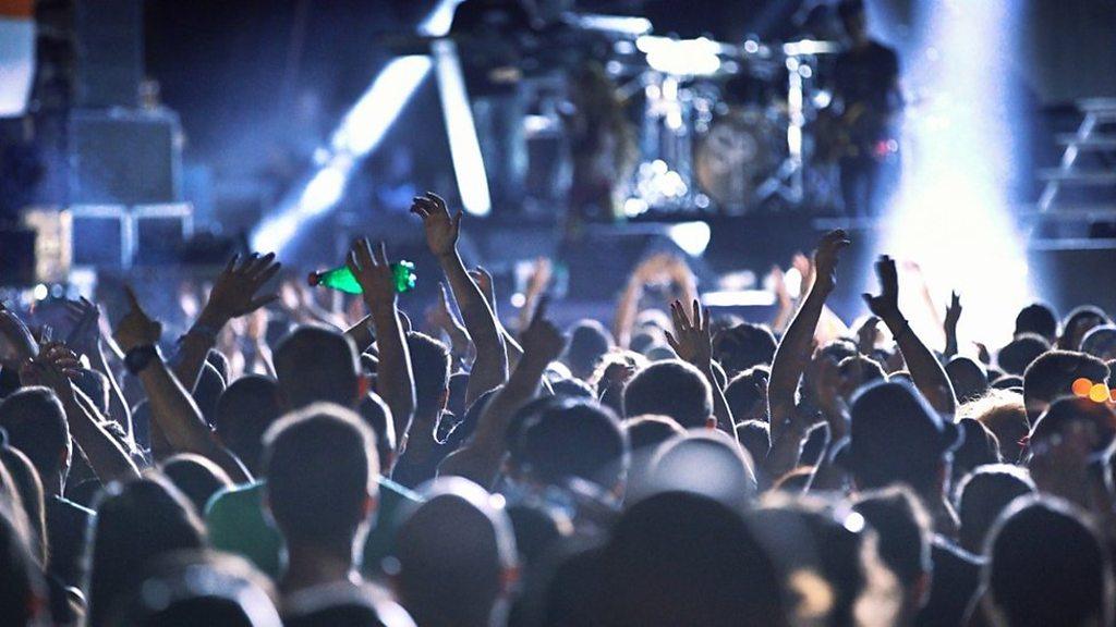 People with their hands raised at a gig